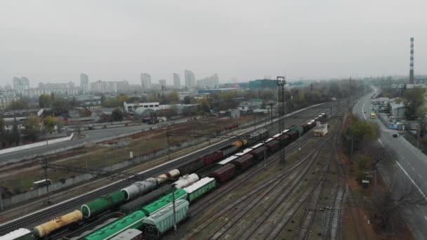 Vue aérienne de la ville industrielle et du train de marchandises circulant le long de la rue avec des wagons remplis de marchandises et de réservoirs de carburant — Video