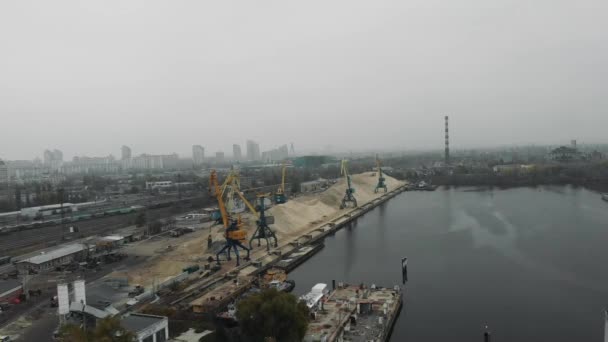 Stavební jeřáby v průmyslovém parku města přesouvají písek z člunu na náklaďák s pískem. Letecký pohled — Stock video