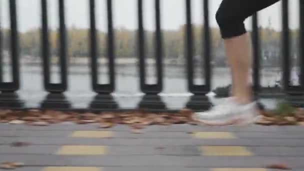 Бегунья бежит быстро и упорно тренируется перед ультрамарафоном, закрывая боковой обзор ног. Спортсмен бегает по городской набережной вдоль реки — стоковое видео