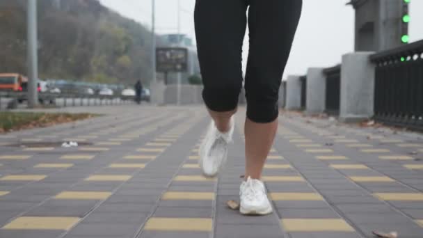 Beyaz profesyonel spor ayakkabılı genç bir kadın nehir boyunca şehir rıhtımında yoğun antrenman yapıyor. Spor kadın sporcusu şehir merkezindeki bankada koşuyor ve spor yapıyor. — Stok video