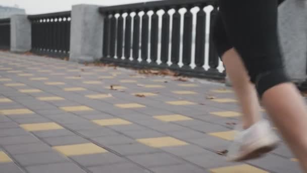 Sportvrouw hardloper atleet met mooie benen in zwart leggins is buiten trainen in de stad op kade. Rennende vrouw. Vrouw joggen snel langs de stadsbank — Stockvideo