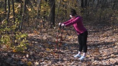 Tombul kadın, sonbahar parkında yürüme antrenmanından önce belini ve kalçalarını esnetiyor. Fitness konsepti