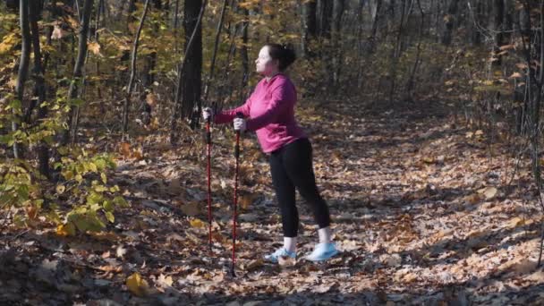 Stretching exercises with nordic walking poles before training in city autumn park. Weight loss concept — Stock Video