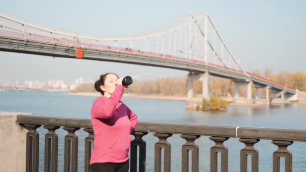 年轻的胖胖的女人们在城市公园里进行了紧张的跑步和北方人的步行训练，然后喝水。 水合物的概念 — 图库视频影像