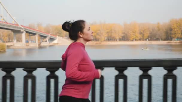 Side kövesse kilátás fiatal aranyos nő könnyű kocogás végig város sétányon felkészülés maraton verseny — Stock videók