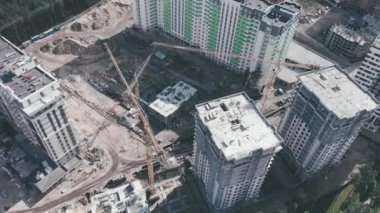 Yeni binalar inşa ediliyor. Gökdelenli inşaat alanındaki yüksek vinçlerin hava aracı görüntüsü. Ormanın ortasında modern apartmanlar inşa ediliyor.