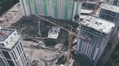 Modern yüksek katlı konut kompleksi yapım aşamasında. Büyük vinçler, hava aracı manzaralı. İnşaat süreci. İnşaatçılar inşaat alanında çalışıyor. Bina yapım aşamasında