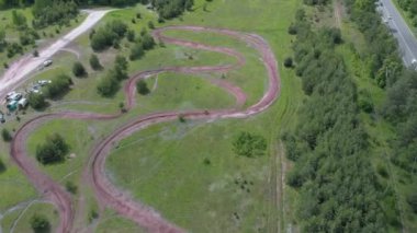 Motosikletli tehlikeli virajlı yolda motosiklet sürüyor. Profesyonel motokros sürücüsü off-road 'a çıkıyor. Motopark 'taki motokros pistinin havadan görüntüsü