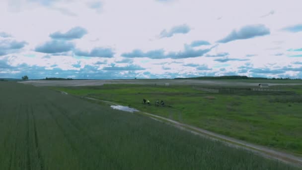 Groupe de cyclistes chevauchant au milieu du terrain, vue aérienne sur drone. Hommes et femmes font du VTT hors route. Personnes actives voyageant à vélo, à vélo sur des vélos dans les champs — Video