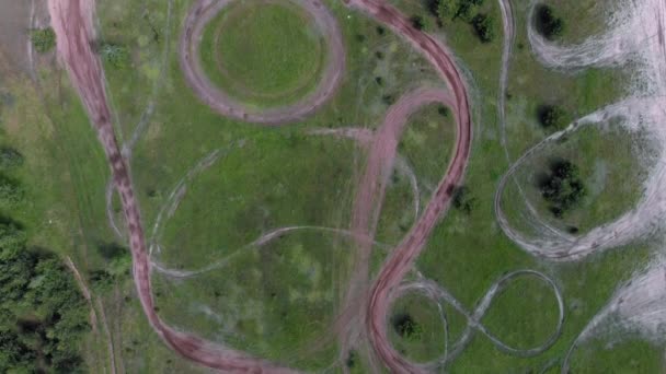 Drone vliegen boven professionele motorcross motorfiets racebaan omgeven door bos. Lege motorcross track met ingekapselde kunststofkringloop, bovenaanzicht — Stockvideo