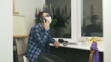 Tıbbi maskeli bir adam iş ortaklarıyla telefonda konuşuyor. Salgın sırasında iş yerinde kalıyor. Erkek serbest çalışan, iş arkadaşlarıyla telefonda konuşuyor ve görevleri tartışıyor.