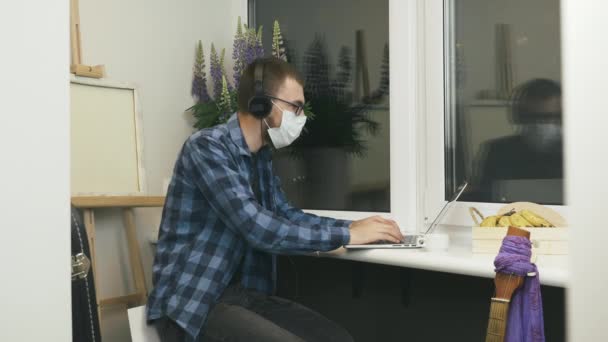 Man in protective mask making online video call by webcam and talking with friends and family staying home on selfisolation during quarantine. Male freelancer making online group video call conference — Stock Video