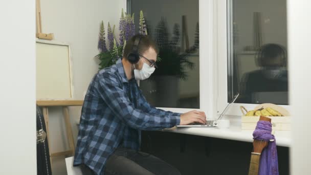 Hombre se quita los auriculares después de trabajar en el ordenador portátil en el balcón por la noche. Hombre en gafas y auriculares acabado para trabajar en proyecto remoto en portátil en casa — Vídeos de Stock