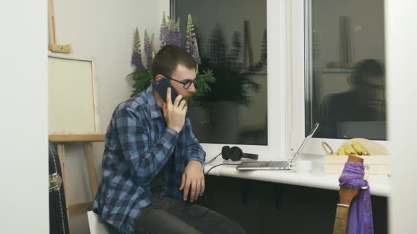 Hombre freelancer hablando por teléfono con los socios, haciendo un trato en el nuevo proyecto remoto. Hombre con gafas hablando por teléfono con amigos que se quedan en casa en aislamiento durante la cuarentena — Vídeos de Stock