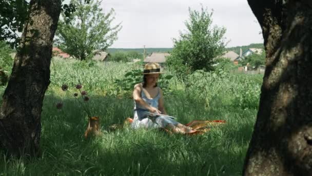 Mujer empezando a trabajar en el ordenador portátil en el jardín verde. Joven morena abriendo cuaderno y empezando a trabajar. Mujer sentada en el parque con ordenador portátil en el día soleado — Vídeos de Stock