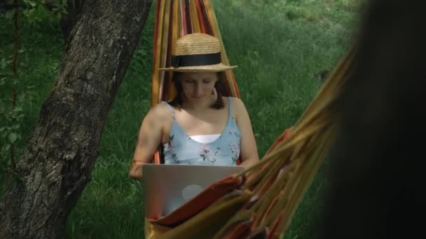 Chica con cuaderno en hamaca. Mujer cerrando el ordenador portátil mientras está acostado en la hamaca en el campo. Joven freelancer femenina terminó de trabajar en el portátil al aire libre — Vídeo de stock