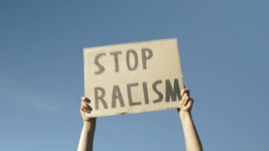 Poster mavi gökyüzüne karşı RACISM 'i durdurur. Eller mavi gökyüzüne karşı 