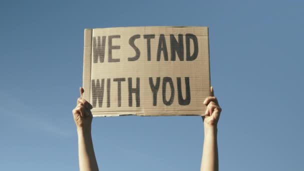 Firmiamo con te contro il cielo blu. Le mani della donna che sventolano poster "We Stand With You". Le vite nere contano protesta pacifica. Rallies contro la brutalità della polizia e il razzismo anti-nero — Video Stock