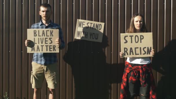Люди з картонними плакатами "Black Lives Matter" і "Stop Racism" у своїх руках. Один протест. Правосуддя в США. Політичний мітинг. Проти жорстокості поліції. Люди протестують за рівні права. — стокове відео