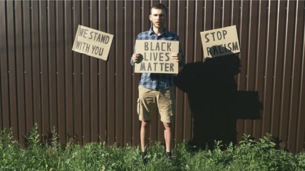 Hombre caucásico sosteniendo letrero "Las vidas de los negros importan" en protesta pacífica. Póster BLACK LIVES MATTER en manos de los hombres. Detener el concepto de racismo. Manifestaciones contra el racismo y la brutalidad policial . — Vídeos de Stock