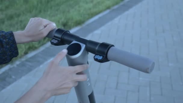 Jeune femme allumant le transport électrique personnel et commençant à monter. Fille allume scooter écologique électrique et va de l'avant dans la rue. Nouvelle génération écologique. Mode de vie sain en ville — Video