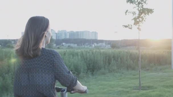 Mujer montando scooter eléctrico personal al atardecer. Chica paseos cargado e-scooter a lo largo de la carretera en el parque. Joven atractiva hembra usando scooter ecológico eléctrico en el paseo marítimo al atardecer. Nueva generación — Vídeos de Stock