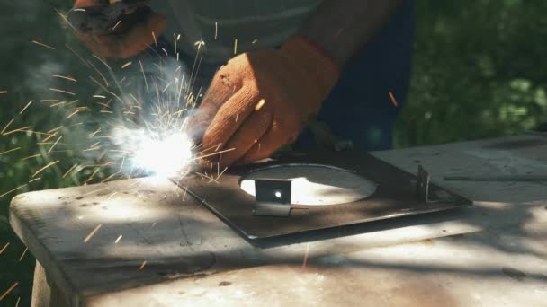 Primer plano de las manos masculinas utilizando la soldadora eléctrica de metal de soldadura para el marco de metal de montaje. Soldador trabaja con acero metálico y hierro utilizando la máquina de soldadura — Vídeos de Stock