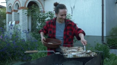 Kadın, mangalda pişmiş balığı, yazlık evin bahçesinde, tabağa koyar. Izgarada balık hazırlıyorum. Aile pikniği. Kızarmış ızgara balık. Barbekü zamanı.
