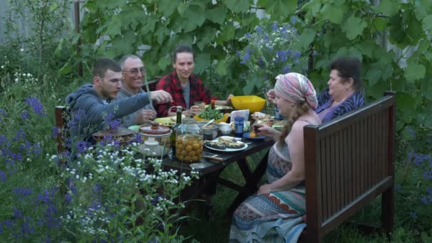 Grande fête de pique-nique en famille. Heureux parents à table sur la cour à l'été, prise de vue du temps. Manger en famille, boire, rire et s'amuser ensemble au pique-nique — Video