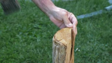 Avluda baltayla odun kesen erkek ellerini kapatın. Beyaz erkek oduncu dışarıda odun kesiyor. Mangal ya da mangal için odun kesen adam.