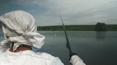 Balıkçılar göle olta attı. Gölde teknede balık tutan bir adam. Nehirde güneşli yaz gününde erkek avının arkası. Balık tutma konsepti. Nehir kıyısında balık tutmak