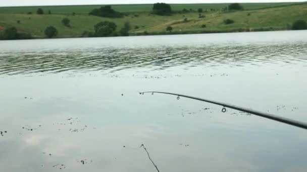 Gros plan de la canne à pêche avec ligne dans l'eau de la rivière ou du lac. Pêche sur le lac. Pêche fluviale en été. Pêche près du rivage — Video