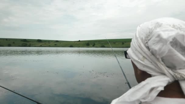 Visser die vis vangt bij de oever van de rivier. Man vissen op meer met hengels. Vissen op het meer. Visserij met behulp van hengels in het reservoir. Recreatie van de mens met vishengel buitenvissen — Stockvideo