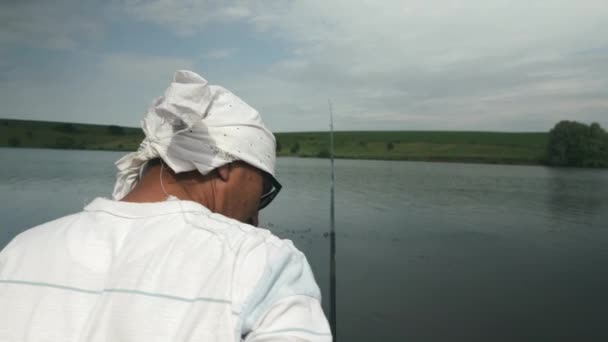 Hombre con caña de pescar la captura de peces en barco en el lago. Pescador pescando en el río. Pesca en el río cerca de la orilla. Pesca en el lago — Vídeos de Stock