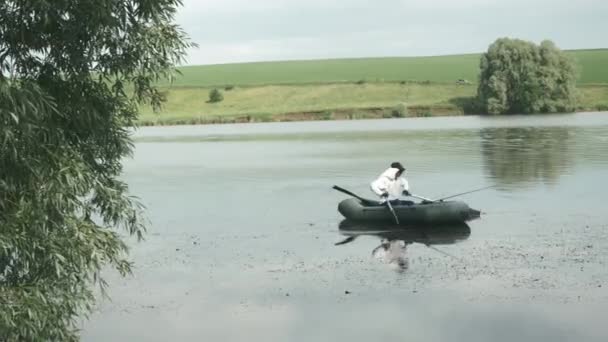 Angeln am See. Fischer segelt im Boot auf dem See. Mann angelt auf See. Männchen fangen Fische an sonnigem Sommertag — Stockvideo