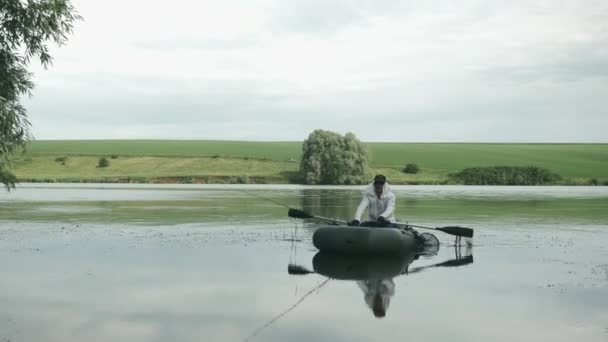 Pesca en el río cerca de la orilla. Vacaciones de verano y concepto de personas. Hombre pescador navegando en barco en el lago. Pesca en el lago. Pesca cerca de la orilla del río — Vídeos de Stock