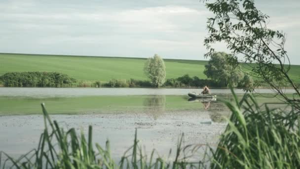 Visser zittend in boot en vissen op meer in de zomer zonnige dag. Vissen op het meer. De mens vangt vis. Concept Levensstijl van de visser — Stockvideo