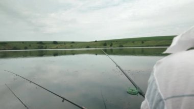 Balıkçı oltalarla gölde dinleniyor. Adam nehirde balık yakalar. Açık havada balık tutmak. Balıkçı yaşam tarzı. Hobiler ve balıkçılık konsepti. Gölde insan eğlencesi