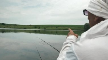 Şişme teknedeki adam su deposunda balık yakalar. Balıkçı elinde olta, açık havada balık tutuyor. Nehir kıyısında balık tutuyorum. Yaz tatili konsepti. Balıkçılık yaşam tarzı