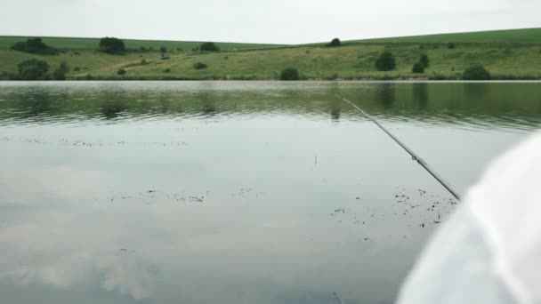 Rybář chytá ryby na řece nebo na jezeře. Mužský rybaření venku. Rybářská prut na vodě. Blízko rybářského člunu. Muž rybaří u břehu řeky — Stock video