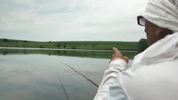El hombre en barco inflable atrapa peces en el embalse. Pescador con cañas de pescar pesca al aire libre. Pesca cerca de la orilla del río. Concepto de vacaciones de verano. Pesca estilo de vida — Vídeos de Stock