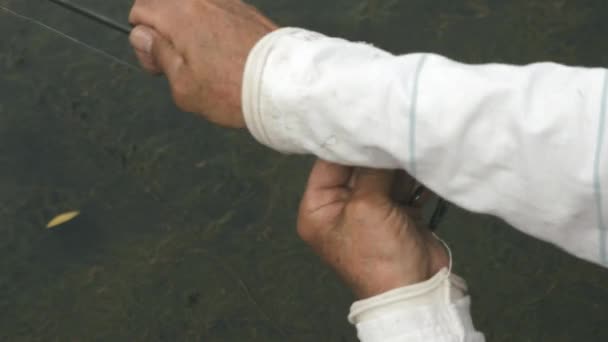 Mužské ruce s rybářskou prutem. Rybář skládá rybářskou prut s rybářským vlasec proti vodě. Rybaření na jezeře. Rybářův koncept životního stylu — Stock video