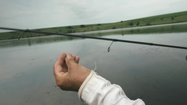 Hengel met meer op de achtergrond. Visser met vishengel, van dichtbij. Visserijconcept. Riviervissen bij de kust. Recreatie visserij — Stockvideo