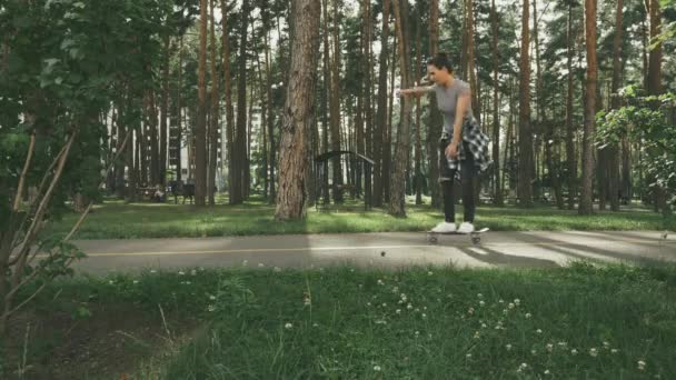 Junge unbeschwerte schöne brünette Hipsterfrau in kariertem Mantel und Jeans, die Spaß beim Skateboardfahren hat. Weibchen lernen Skateboard fahren im Park. Junge glückliche Mädchen skateboarden — Stockvideo