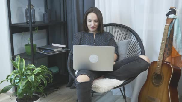 Mujer de negocios terminando de trabajar en el ordenador portátil en la oficina en casa. Chica relajante en silla en apartamento moderno. freelancer femenina trabaja en cuaderno en silla acogedora. Trabajo desde casa . — Vídeos de Stock