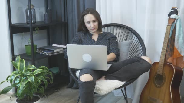 피곤 한 사업가가 가정 사무실의 의자에서 노트북 컴퓨터로 일하고 있습니다. 젊은 여성이 가정 사무실에서 피곤 해 하고 있습니다. 컴퓨터에서 일하는 여자 프리랜서, 피곤하고 짜증나는 모습 — 비디오