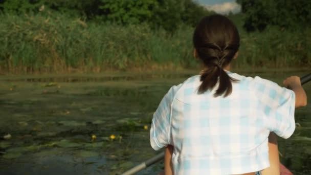 Молодая брюнетка плавает на каяке по реке в летний солнечный день. Женщина турист исследует реку и красивый пейзаж на каноэ. Счастливая девушка плавает на каяке по реке. водный туризм — стоковое видео