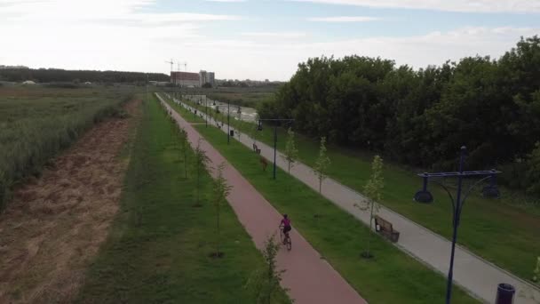 Meisje draait op de racefiets op een leeg fietspad langs de rivier. De vrouw fietst op de promenade. Gezond levensstijl en sport concept. Vrouwelijke fietser fietst. Atleet is fietsen op de fiets — Stockvideo
