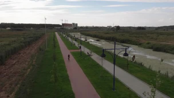 Ciclista profissional feminino está andando rápido na bicicleta no caminho do ciclo. Mulher feliz em passeios de vestuário de ciclismo em bicicleta de estrada ao ar livre. Jovem está pedalando de bicicleta através do calçadão, em roupa elegante — Vídeo de Stock