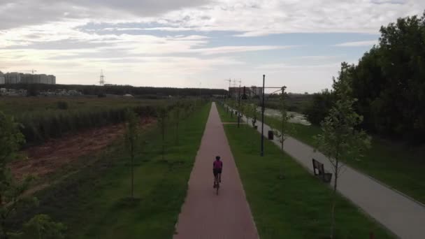 Mujer está en bicicleta en carril bici cerca del paseo marítimo. Ciclista profesional pedalea en bicicleta de carretera a lo largo del río. La atleta cabalga en bicicleta y hace entrenamiento. Chica feliz está en bicicleta — Vídeos de Stock